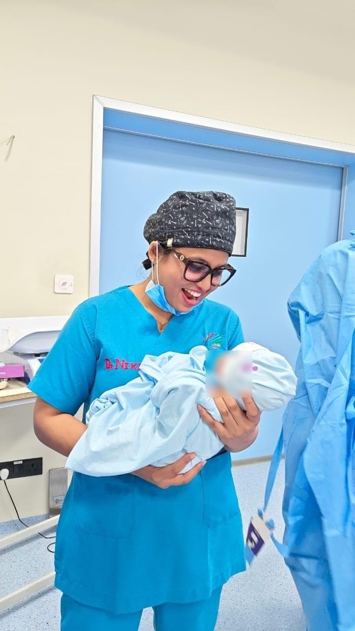 Dr. Nikita holding a newborn in the delivery suite