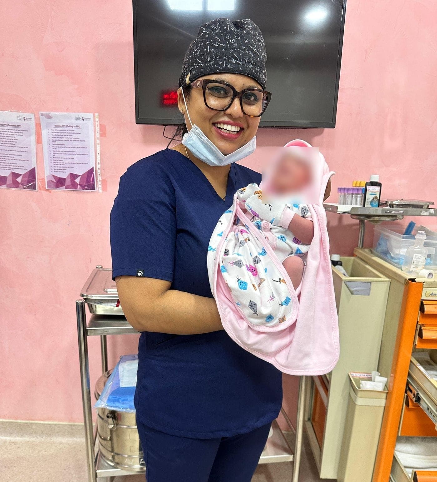 Dr. Nikita in scrubs holding a newborn after delivery
